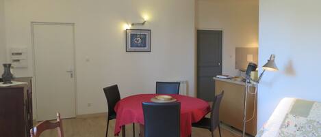 A compact room with a dining table, chairs, a sofa, and a lamp.