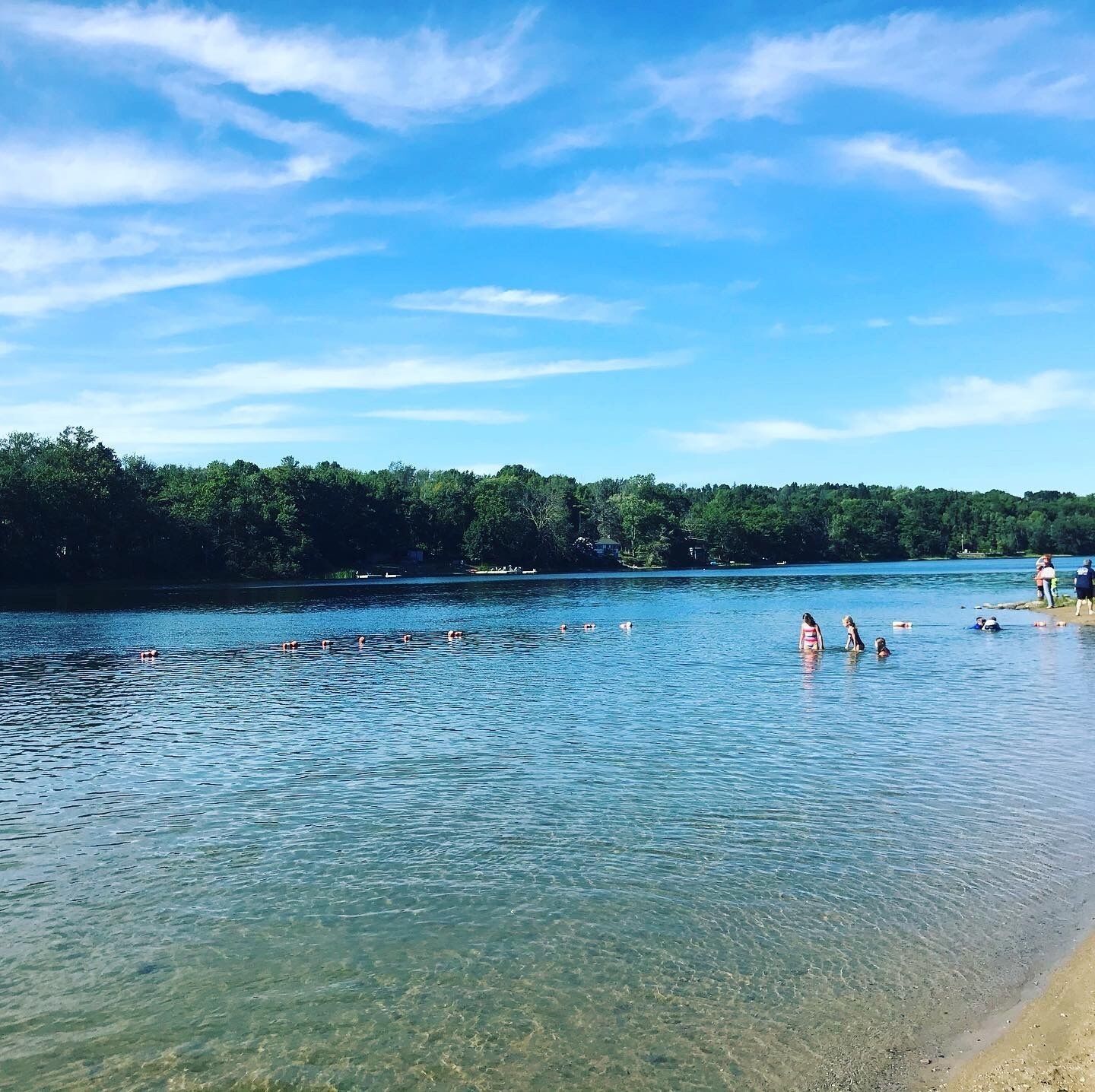 Un lago de aguas cristalinas, rodeado de árboles y un cielo despejado.