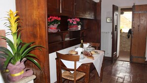 A dining area with wooden cabinets, a table set with bread, wine, and flowers. - Vacation in a former monastery from the 14th century - Kamino apartment (Colle di Val d’Elsa)