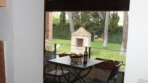 A patio with a table and chairs, a small stone oven, and a view of a garden. - Vacation in a former monastery from the 14th century - Kamino apartment (Colle di Val d’Elsa)