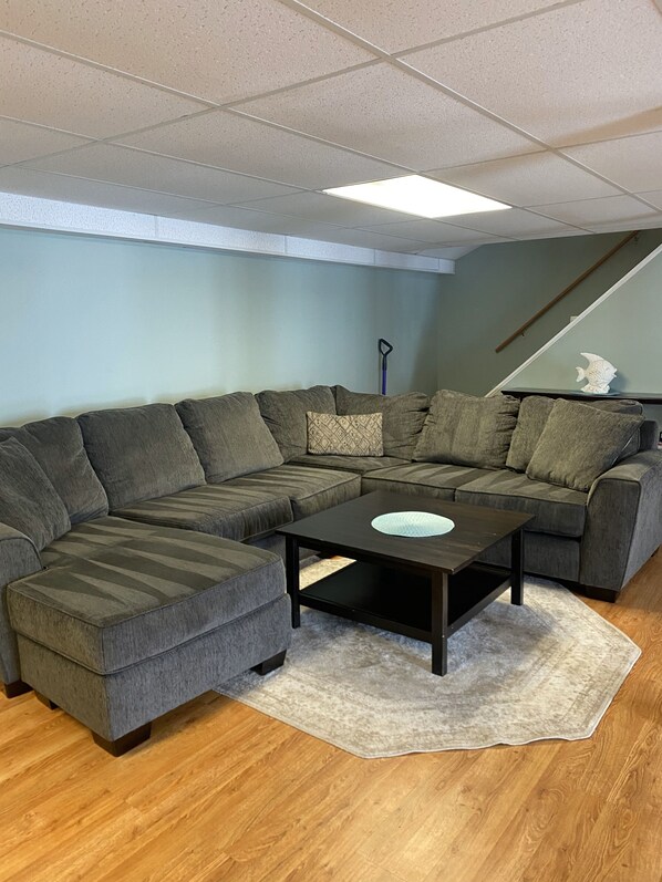 A living room with a sectional sofa, a coffee table, a rug, and a fish sculpture on the wall. - Private and Calming Waterfront to the Rescue! (Augusta)