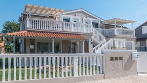 A two-story house with a balcony, a covered patio, and a gated entrance. - Apartment Tena (Ližnjan)