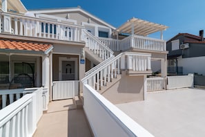 A two-story house with a balcony, a staircase, and a door. - Apartment Tena (Ližnjan)
