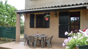 Eine Terrasse im Freien mit Tisch und Stühlen, einem hängenden Blumentopf und einem Topfpflanzen.