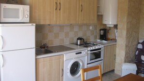 A compact kitchen with a microwave, oven, washing machine, and a coffee maker. - F3 feet in the water. 50 m from the beach (Sagone)