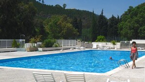 Une piscine bordée de chaises longues blanches, avec un mur de pierre en arrière-plan.