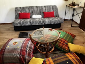 Ein Wohnzimmer mit einer Couch, einem Glastisch und farbenfrohen Kissen.