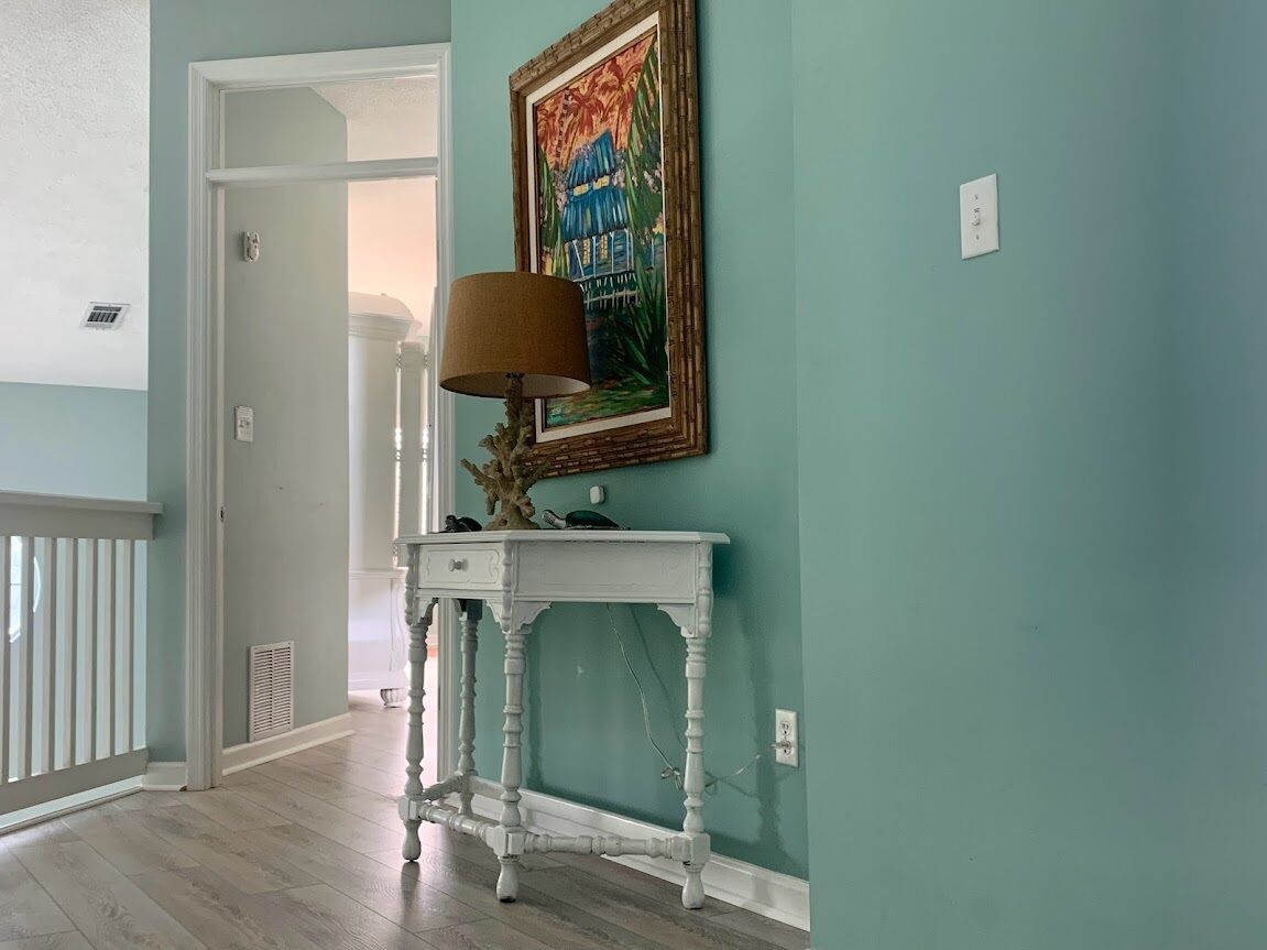 A hallway with a white console table, a lamp, and a framed painting on the wall.