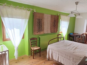 Quarto com uma cama, duas cadeiras, uma mesa e um radiador.