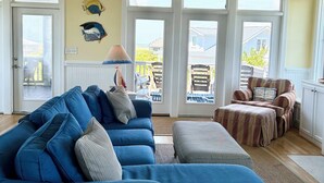 A living room with a blue sectional sofa, a striped ottoman, and a ceiling fan. - NOW AVAILABLE LABOR DAY, OCEAN views, 2 KING masters. 2 clubs- separate purchase (Bald Head Island)