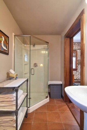 A modern bathroom with a glass-enclosed shower, a sink, and a towel rack. - The Coach House Circa 1755 (Charleston)