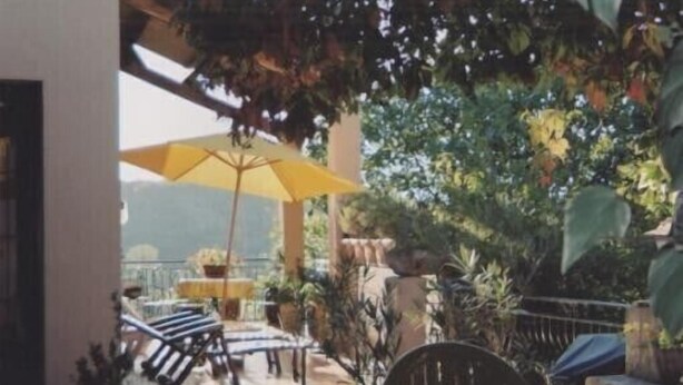 A patio area with a yellow umbrella, lounge chairs, and potted plants. - Country cottage "Le Romarin" (Lagorce)
