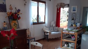 A cozy kitchen with a dining area, featuring a table with a white tablecloth, chairs, a small plant, and a window with curtains. - Country cottage "Le Romarin" (Lagorce)