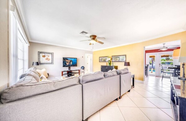 A living room with a grey sectional sofa, a ceiling fan, and a TV. - Beautiful & Waterfront , Gorgeous Intercostal Home (Pompano Beach)