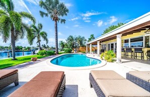 A pool area with lounge chairs, a covered patio, and palm trees. - Beautiful & Waterfront , Gorgeous Intercostal Home (Pompano Beach)