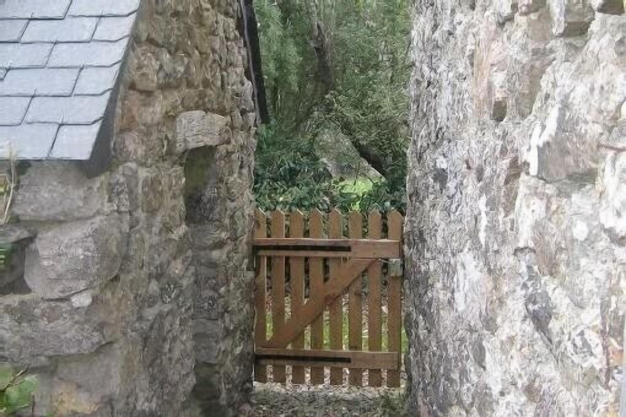 Un étroit passage en pierre, surmonté d’une porte en bois.