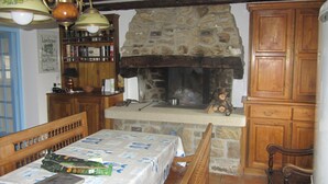 Eine rustikale Küche mit Kamin aus Stein, Holzschränken und einem Tisch, der mit einer Tischdecke und Speisen gedeckt ist.