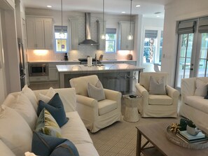 Relax in this open-plan living space featuring a cream-colored sofa, armchairs, and a central island with a sink.