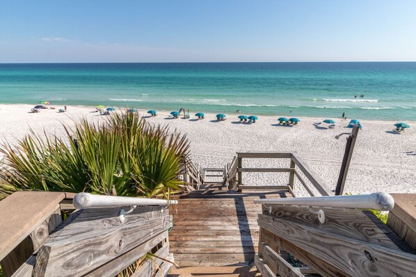Walk along the boardwalk to the sandy beach, where umbrellas provide shade and the ocean offers a calm view.