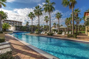 Relax by the pool surrounded by palm trees and lounge chairs.