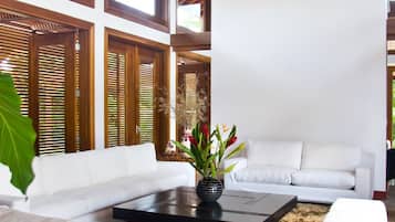 A modern living room with a white sofa, a black coffee table, and a decorative vase with flowers.