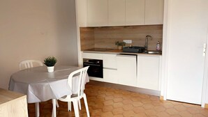 Eine kleine Küche mit weißen Schränken, einer Holz Arbeitsplatte, einem Spülbecken und einem Essbereich mit Tisch und Stühlen.