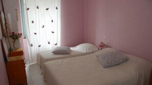 A bedroom with two beds, a dresser, and a window with curtains. - Quiet, restful gîte in town. Everything is less than 500m away on foot! (Beaumont-De-Lomagne)