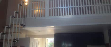 A kitchen with a black refrigerator, a white stove, and a white sink. There is a white railing on the balcony.
