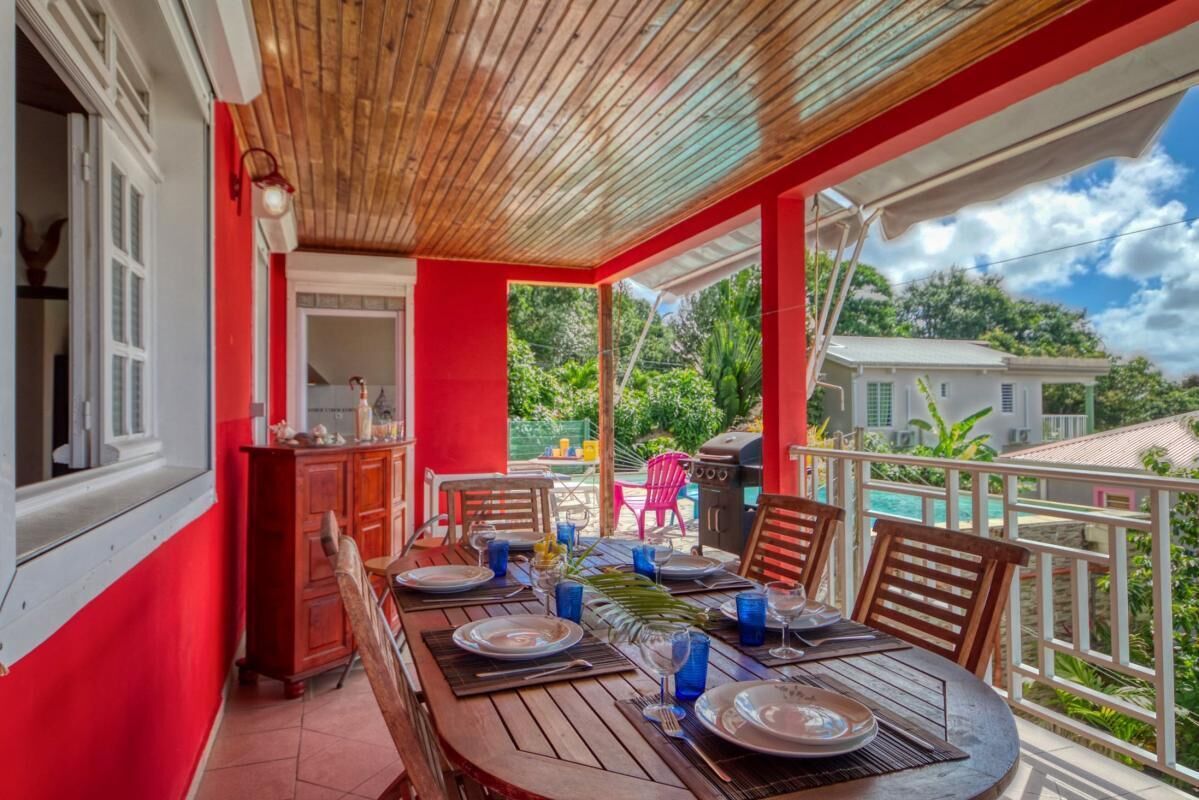 A dining area with a wooden table set for four, surrounded by red walls and a wooden ceiling.
