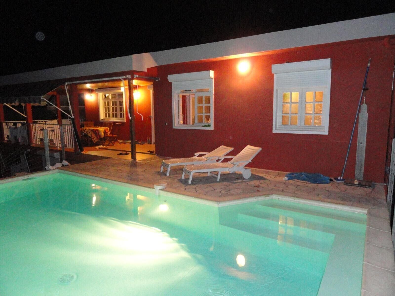 A swimming pool with lounge chairs and a covered seating area.