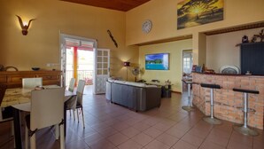 A spacious living area with a dining table, a sofa, and a kitchen area with a bar. - Paradyse-conditioned luxury villa, Saint-luce Martinique Pool (Sainte Luce)