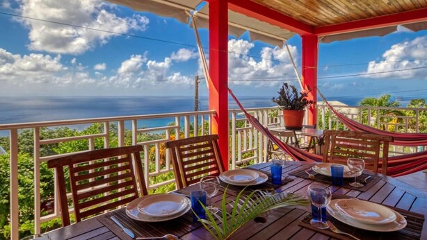A wooden deck with a table set for dining, overlooking a scenic view of the ocean. - Paradyse-conditioned luxury villa, Saint-luce Martinique Pool (Sainte Luce)