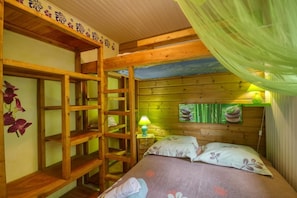 A wooden bunk bed room with a ladder, a green lamp, and a wall with a picture of food.