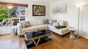 A modern living room with a sectional sofa, a glass coffee table, and a floor lamp. - 2 Bedroom Condo Only 1 Block to UCB (Berkeley)