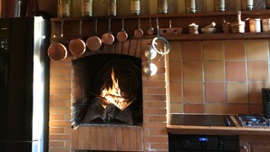 A kitchen with a brick fireplace, hanging pots, and wine bottles on the wall. - Maison de Maître, manor house style, on the banks of the Lot, countryside, heated swimming pool, tennis court, sauna (Casseneuil)