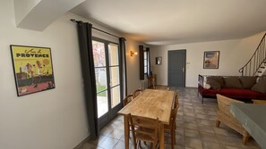 A dining area with a wooden table and chairs, a red sofa, and a staircase leading to another level.
