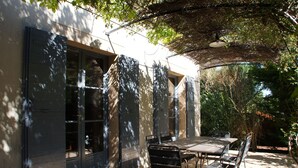 An outdoor patio with a table and chairs, a pergola providing shade, and a view of the surrounding trees. - charming house in Provence (Beaumes-De-Venise)