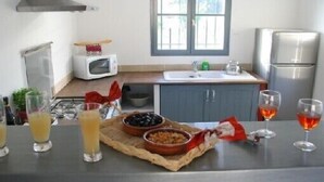 A kitchen with a microwave, sink, and stainless steel refrigerator. There are glasses of orange juice and wine on the counter. - charming house in Provence (Beaumes-De-Venise)
