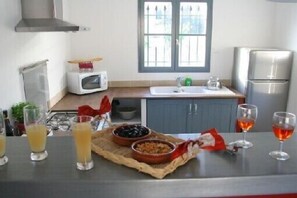 Eine Küche mit Mikrowelle, Spüle und einem Edelstahl-Kühlschrank. Auf der Arbeitsfläche stehen Gläser Orangensaft und Wein.