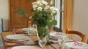 A dining table set with plates, glasses, and a vase of flowers. - charming house in Provence (Beaumes-De-Venise)