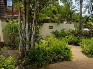 A pathway surrounded by lush greenery and palm trees, leading to a building with a sign indicating a private area. - 1BR/2BA Maui Kamaole/Wailea Border. K Cluster @ Tropical Pool! (Kihei)
