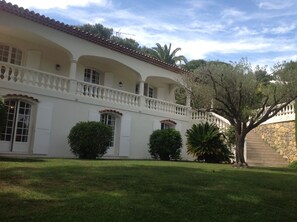 A white building with a tiled roof, multiple balconies, and a stone staircase. - Luxurious, gated villa with panoramic views of the Bay of Cannes, swimming pool, garden, 8 minutes from the beach (Vallauris)