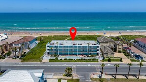 Un hotel con un patio central, rodeado por una playa y vistas al océano.