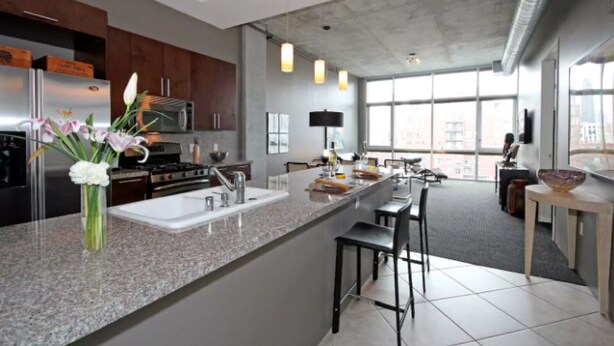 A modern kitchen with granite countertops, stainless steel appliances, and a large window providing natural light.