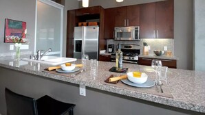 A modern kitchen with granite countertops, stainless steel appliances, and dark wood cabinets.