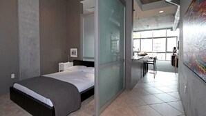 A modern hotel room with a bed, a desk, and a chair.
