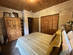 A wooden-paneled bedroom with a bed, wardrobe, and a cabinet with books. - The Sunny Side House 4 bedroom (Alleghany)