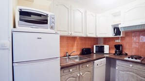 A compact kitchen with white cabinets, a built-in oven, a microwave, a coffee maker, and a dishwasher. - 2 Bedroom Cottage - Garden View (La Chapelle-Geneste)