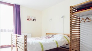 A single bed with a wooden frame, a white mattress, and a green-striped blanket. There is a wooden wardrobe with a hanging rod to the right. - 2 Bedroom Cottage - Garden View (La Chapelle-Geneste)
