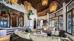 A spacious living area with a large sofa, a coffee table, and a view of the ocean through large windows. - Villa Violeta Luxurious Secluded Beachfront Hideaway. Weekly & Monthly discounts (San Francisco)